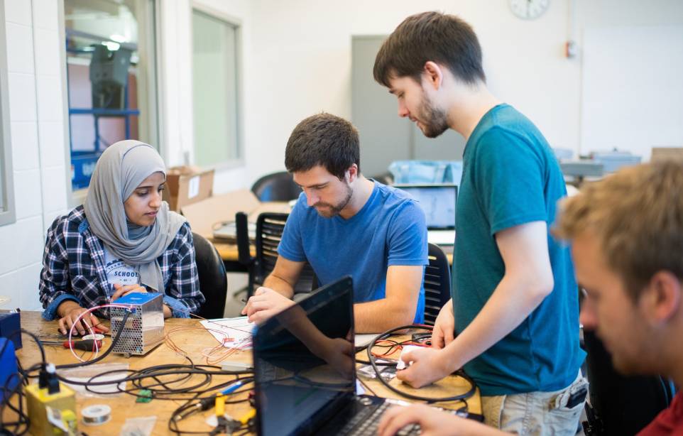 Students working together on a hands-on computing project in a lab setting, with a caption describing Grand Valley State University's School of Computing offering knowledge and real-world experience to undergraduates in a tech-driven world, fostering innovation, creativity, and leadership.